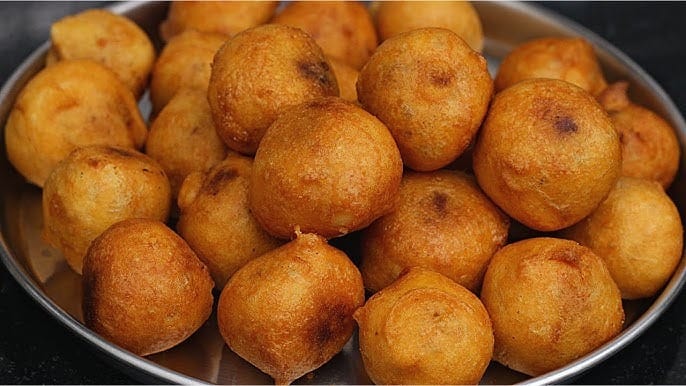 Poornalu - Deep-fried dumplings filled with chana dal and jaggery, encased in a crispy rice flour dough, a traditional South Indian sweet.